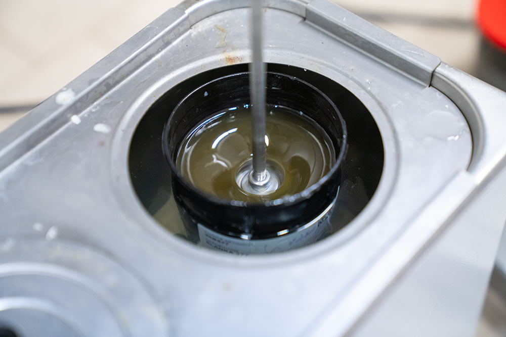 Test su campione di colla a base organica, la colla viene miscelata da uno strumento mentre è a bagno in un liquido a temperatura controllata